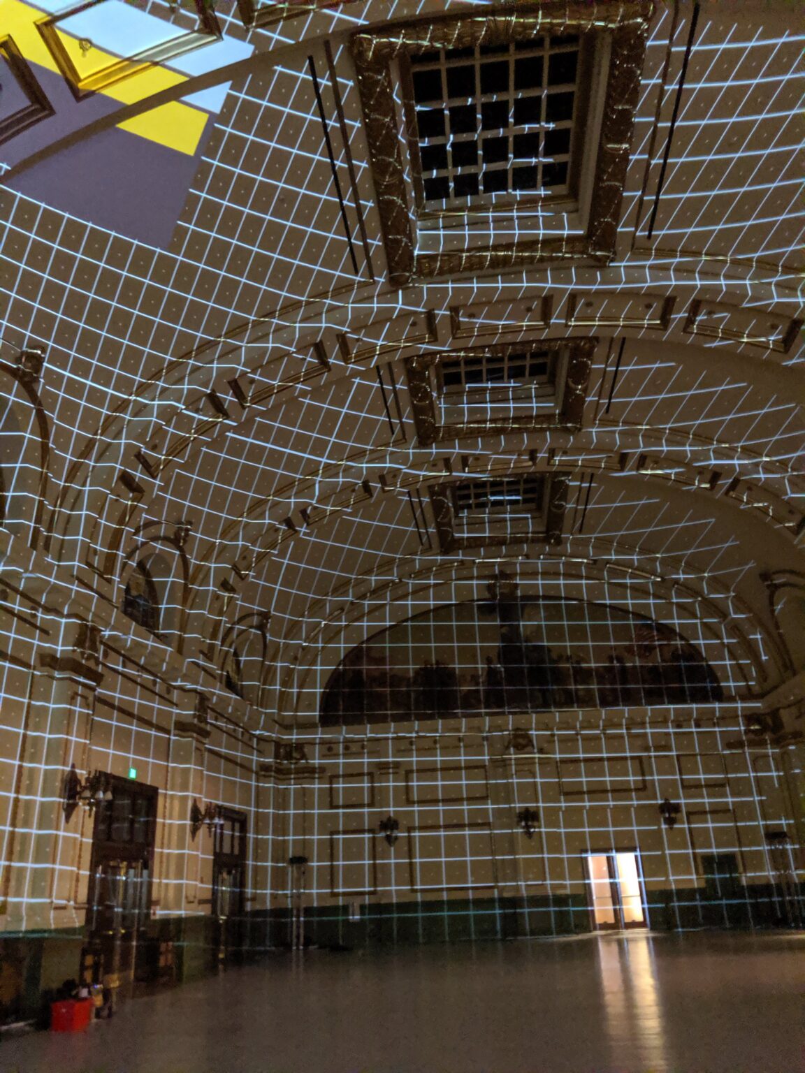 White grid projection mapping covering the vaulted ceiling and walls of an ornate historic hall at Illuminate Arts Festival