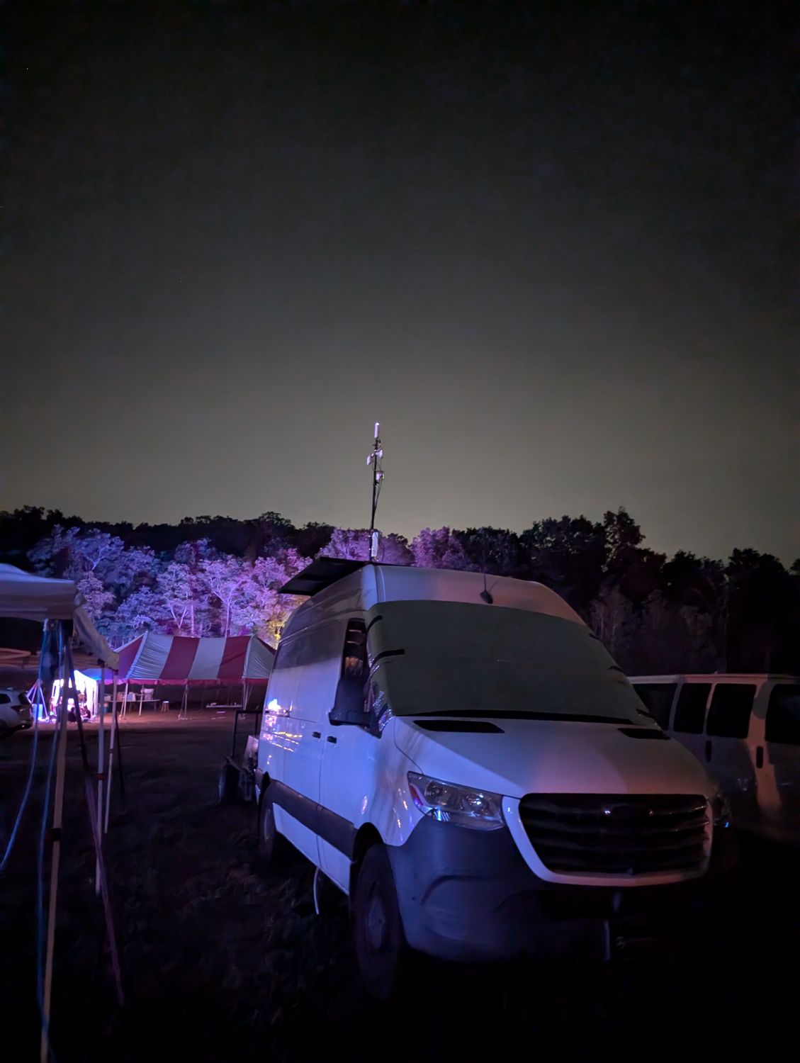 Van with roof-mounted mast at a festival at night
